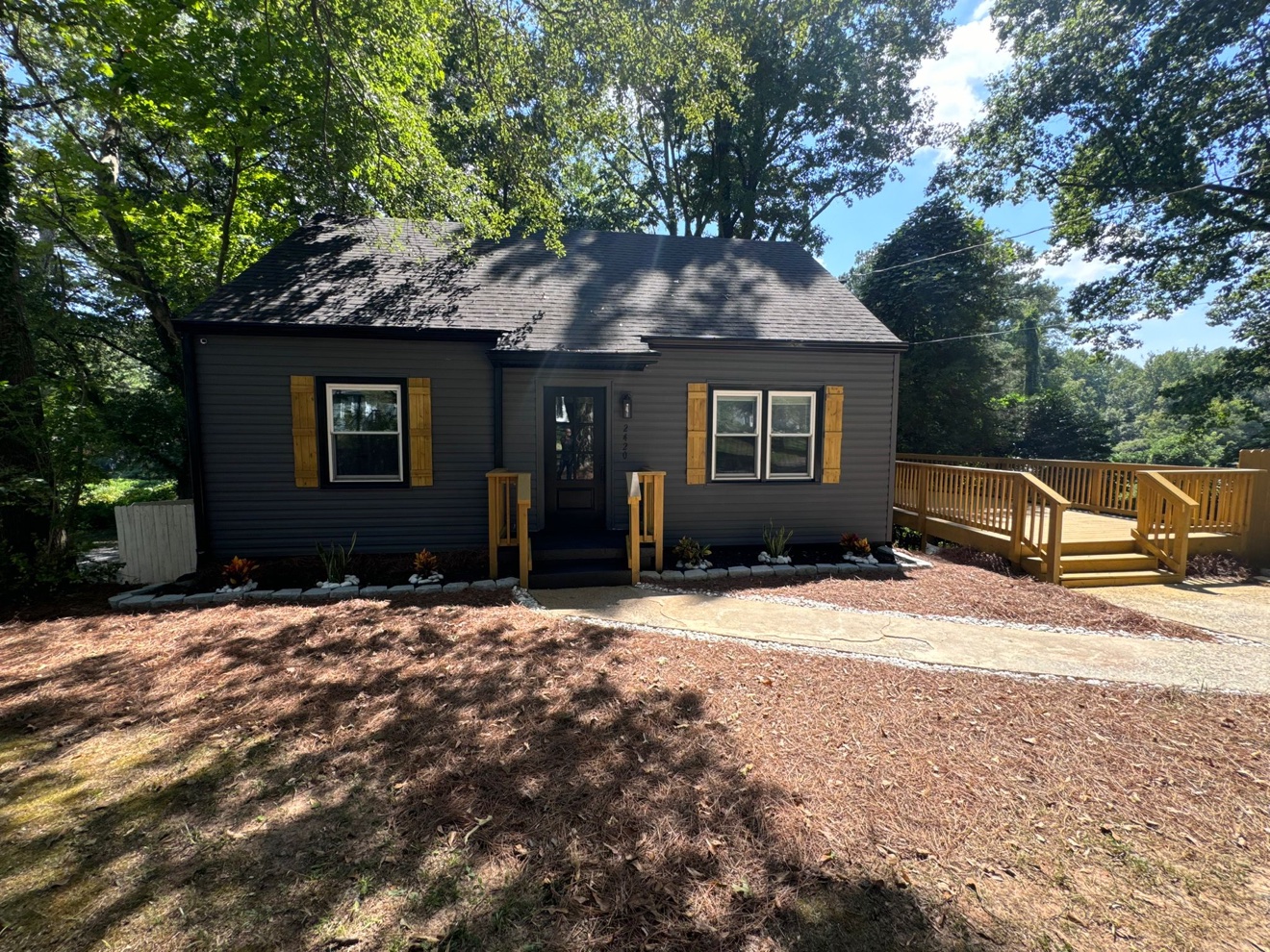 Home exterior repainted dark gray with natural wood shutters