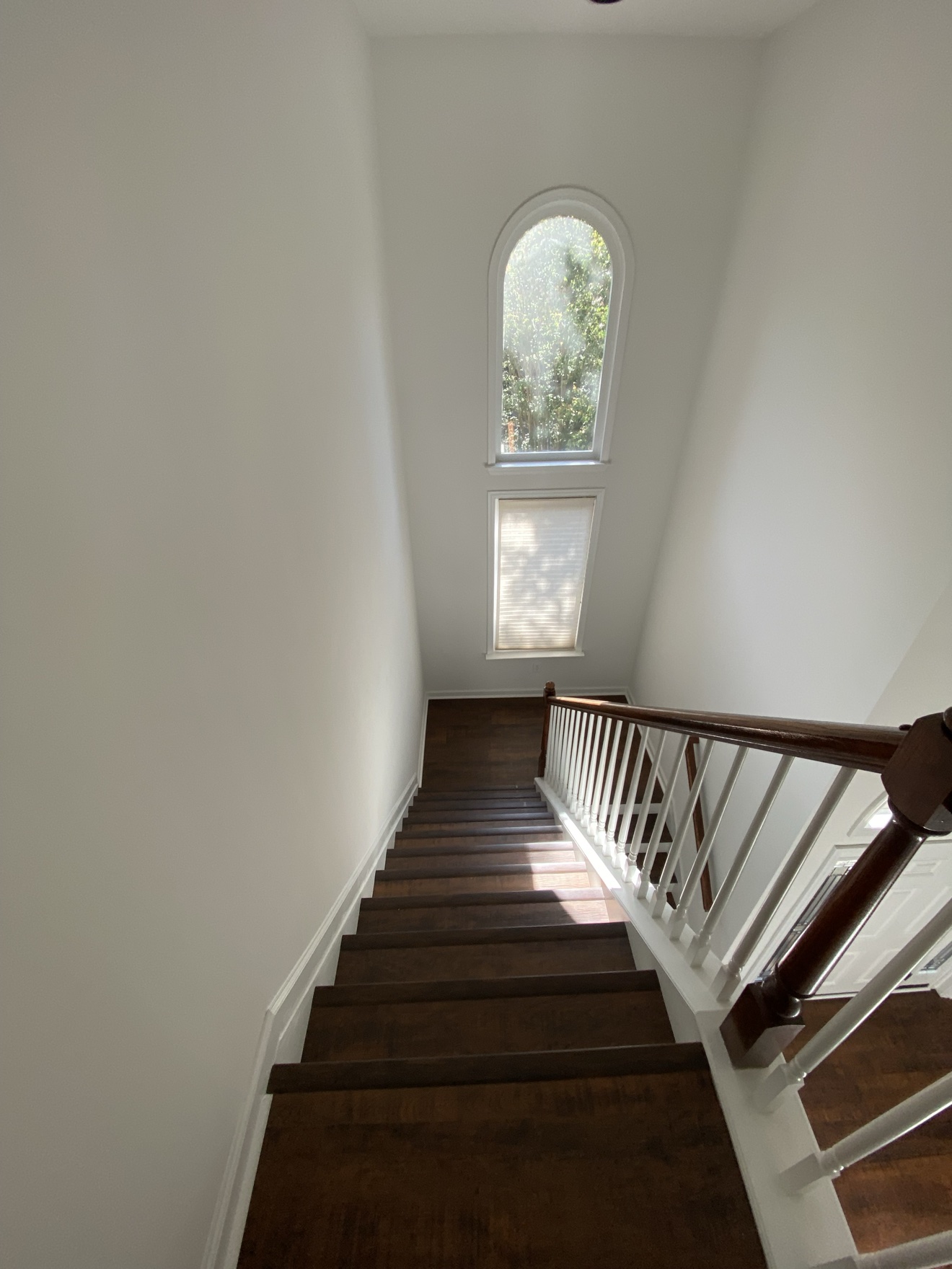 The same staircase after — dark wood treads, white walls and freshly painted railings