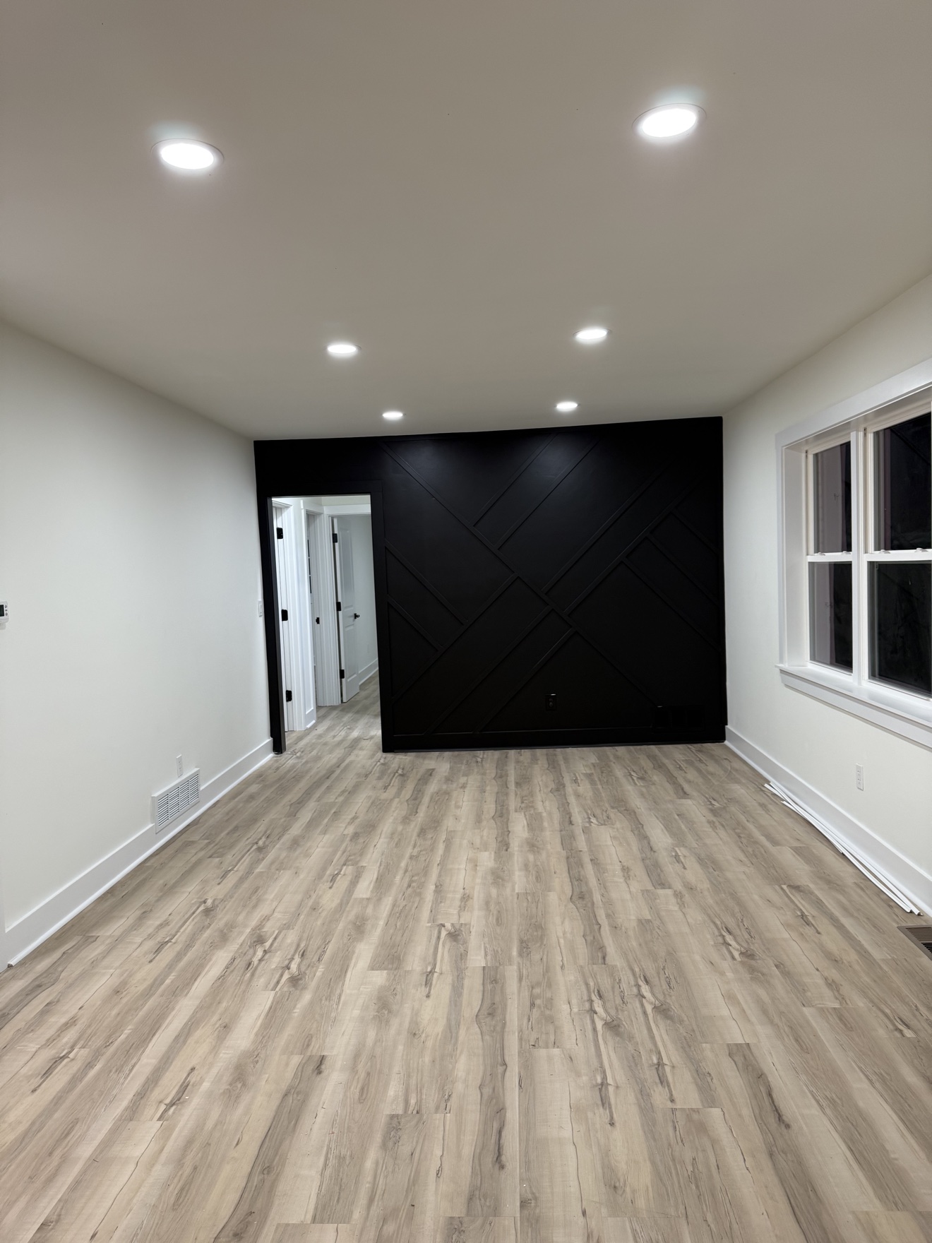 Room with a black geometric accent wall and light wood-look floors