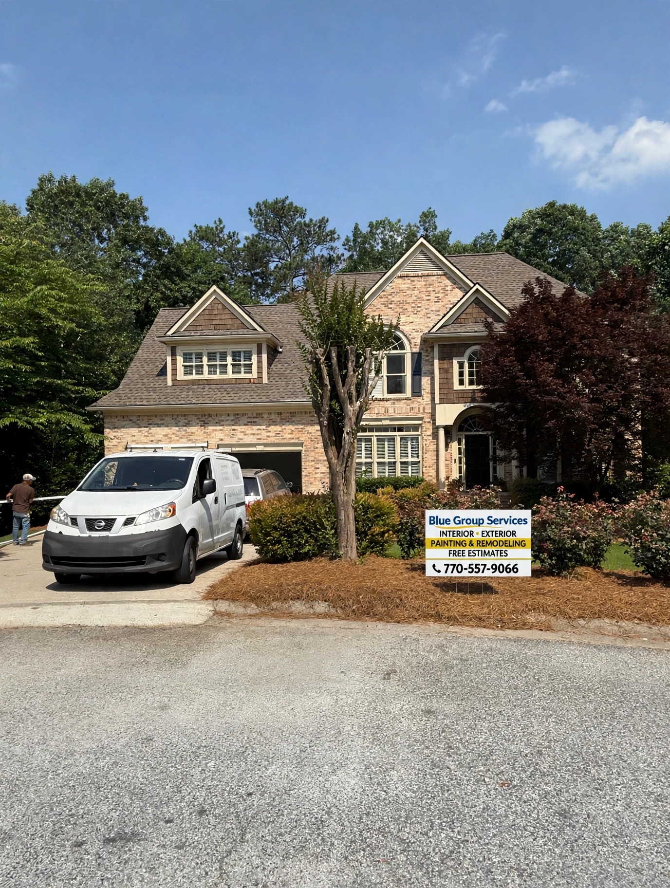 Brick home repaint in progress with the Blue Group van and yard sign out front